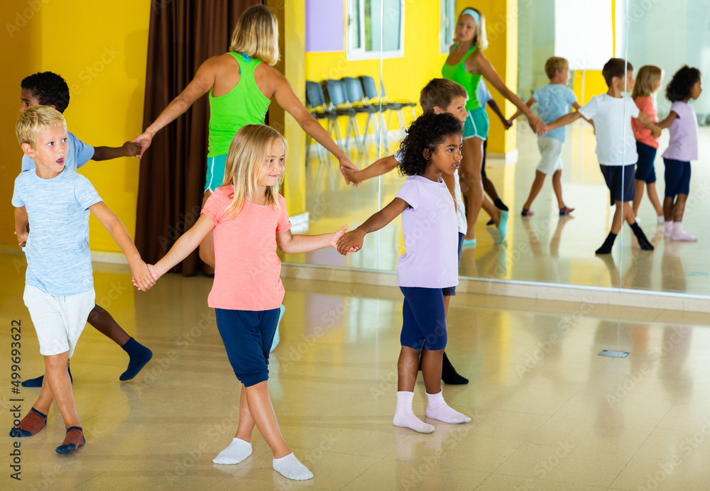 Happy kids and female teacher dancing together in studio at elementary school. High quality photo