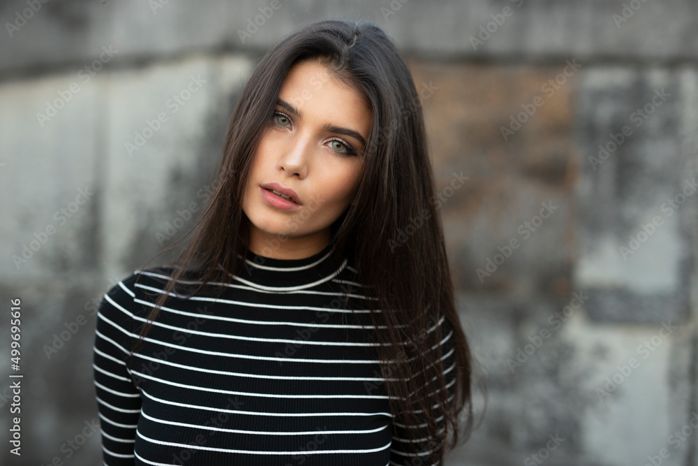 Young woman with straight brunette hair and makeup, looking at camera, over black old wall background. Young woman with straight brunette hair and makeup, looking at camera, over black old wall background.