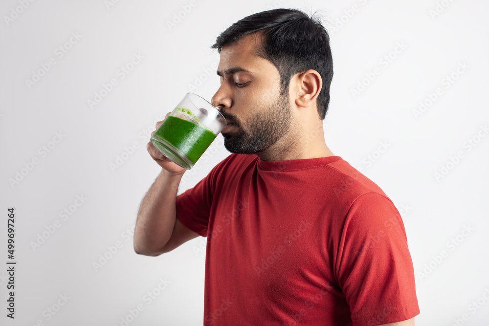 healthy food eating, slim fit indian man drinking wheat grass juice in white background healthy food eating, slim fit indian man drinking wheat grass juice in white background