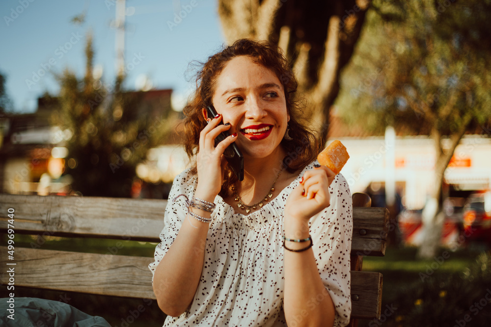 Mujer comiendo un helado y hablando por telefono haciendo turismo. Concepto de turismo y tecnología. Mujer comiendo un helado y hablando por telefono haciendo turismo. Concepto de turismo y tecnología.