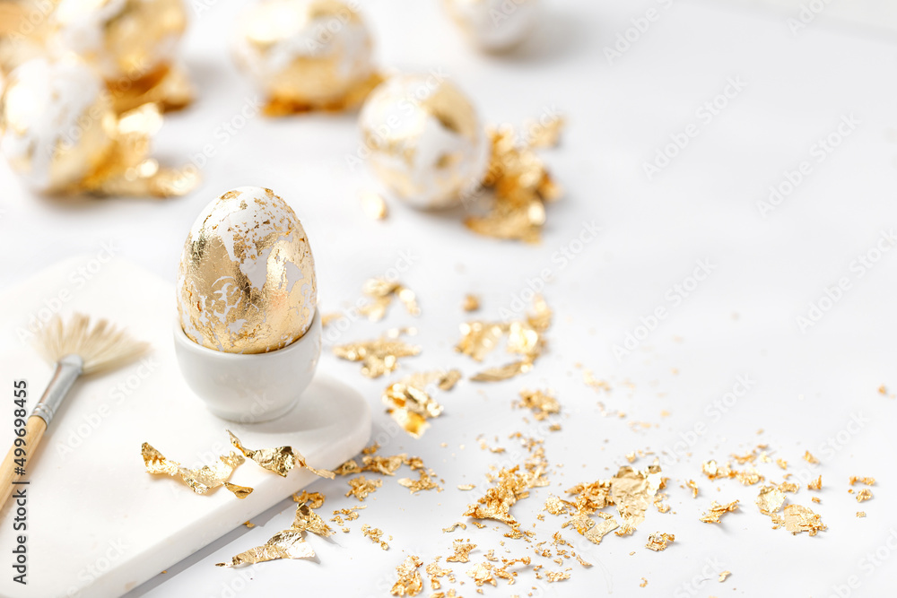 Easter white egg decorated with golden potal on white background. Eeaster diy concept. Easter white egg decorated with golden potal on white background. Eeaster diy concept.
