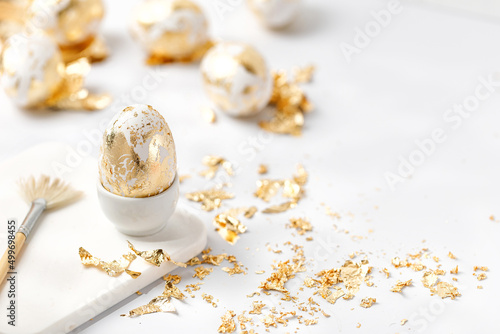 Easter white egg decorated with golden potal on white background. Eeaster diy concept.