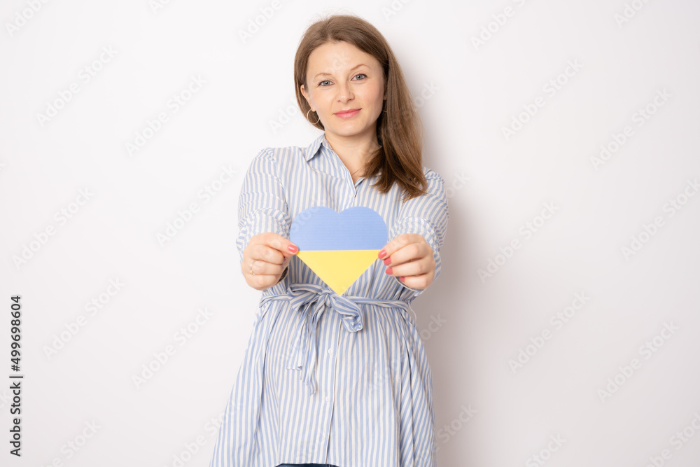 Young smiling pregnant woman showing ukraine paper heart standing isolated over white background. Young smiling pregnant woman showing ukraine paper heart standing isolated over white background.