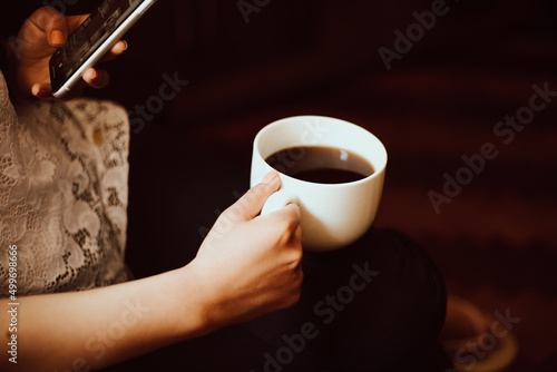 Mano de mujer sosteniendo una taza de café y el teléfono. Concepto de estilo de vida y tecnología photo