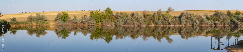 Landscape with trees, reflecting in the water.