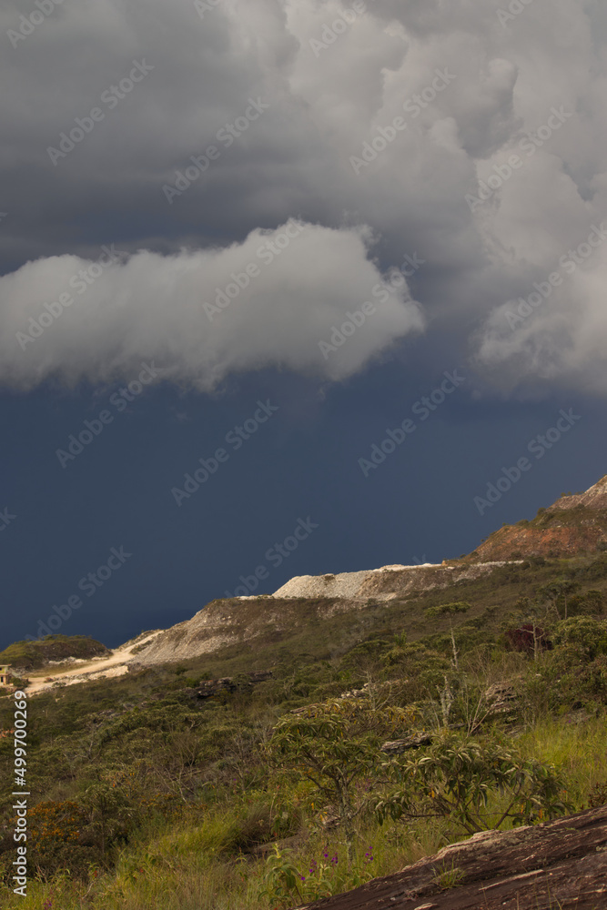 Fototapeta premium open pit mine on the slopes of a hill, under a stormy sky.