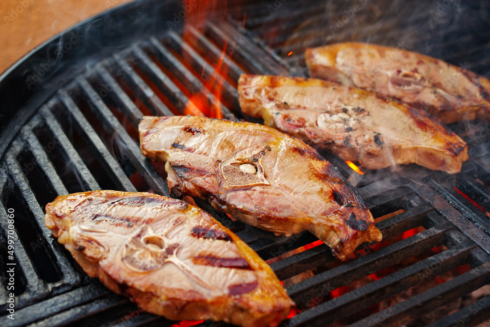 Raw lamb saddle back chop steak grilled as close-up on a charcoal grill with fire