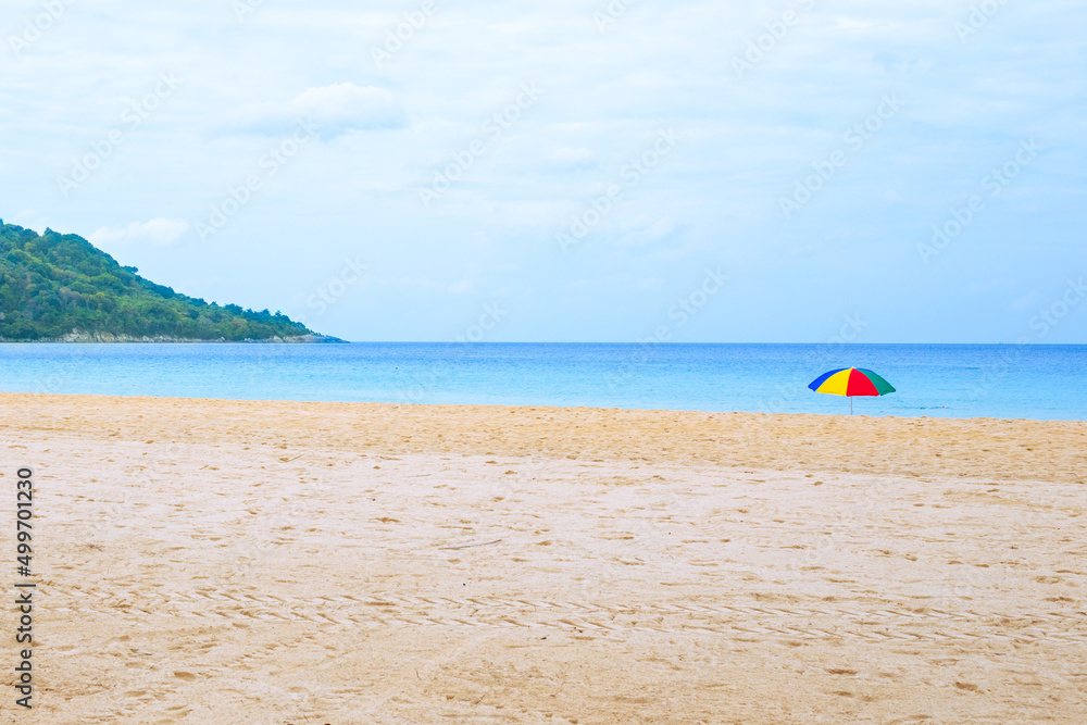 Empty sandy beach with bright umbrella and mountain. Travel and tourism