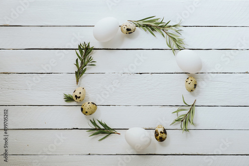 Easter decoration. Circle Easter frame of natural coolor easter eggs on white wood background with space for text. Top view, flat lay photo