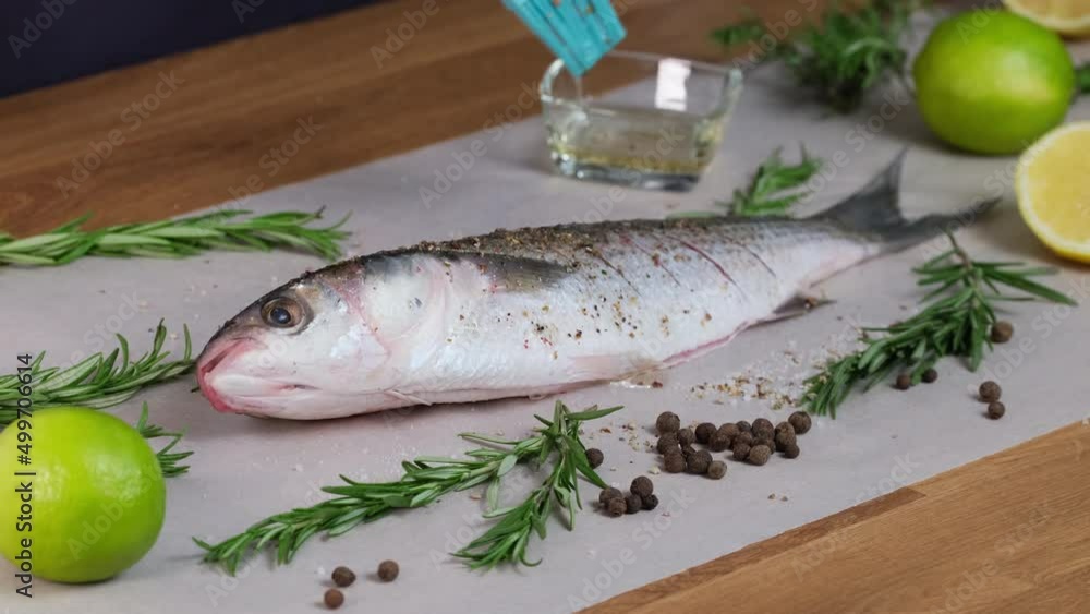 Silicone brush greases raw mullet fish with olive oil. Preparing fresh