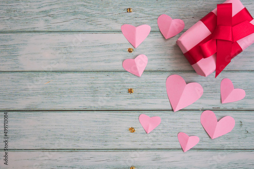 Regalo con corazones rosas en mesa de madera photo