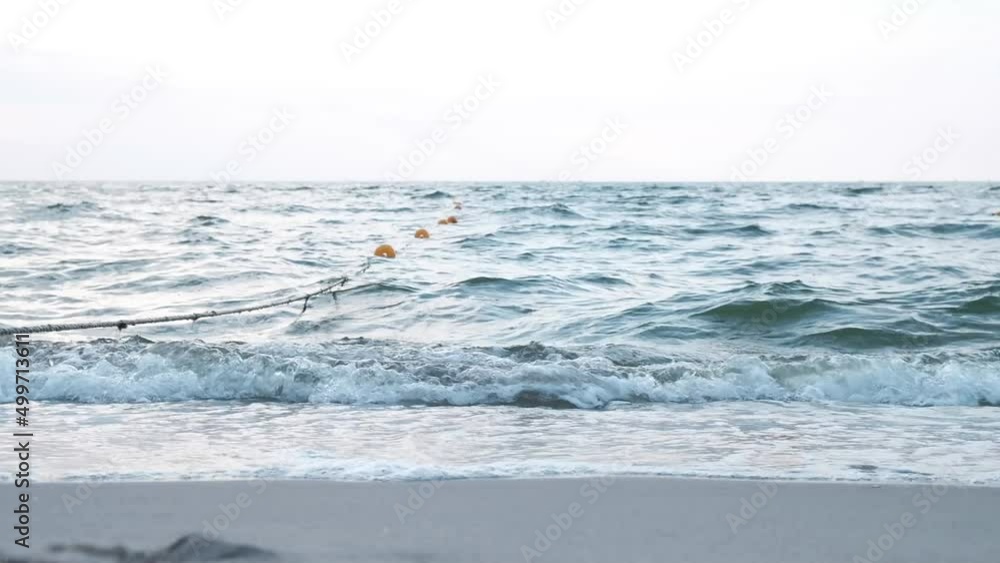 Buoys on a rope by the sea. Waves hit the sandy shore. beautiful seascape with blue waves Buoys on a rope by the sea. Waves hit the sandy shore. beautiful seascape with blue waves