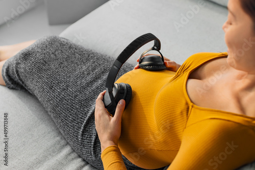 Photo Pregnant woman holding headphones on belly listening to music for unborn baby brain development
