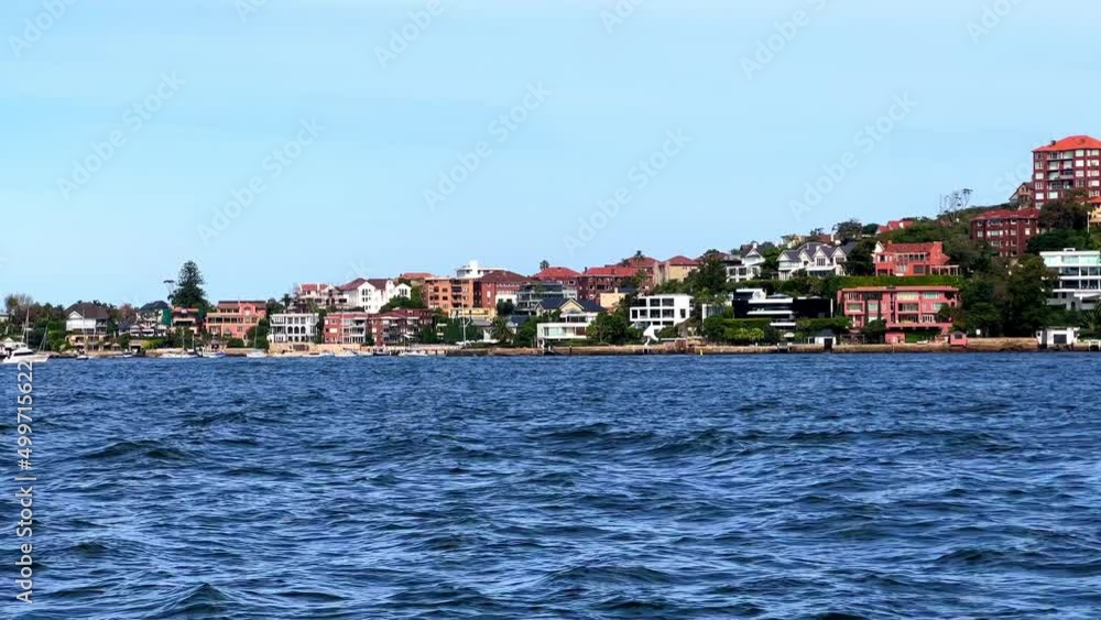 Sydney Harbour foreshore on a party cloudy sky. viewed from ferry on way to Many, you can see apartments, wealthy luxury houses, yachts boats beaches and cliffs NSW Australia Sydney Harbour foreshore on a party cloudy sky. viewed from ferry on way to Many, you can see apartments, wealthy luxury houses, yachts boats beaches and cliffs NSW Australia