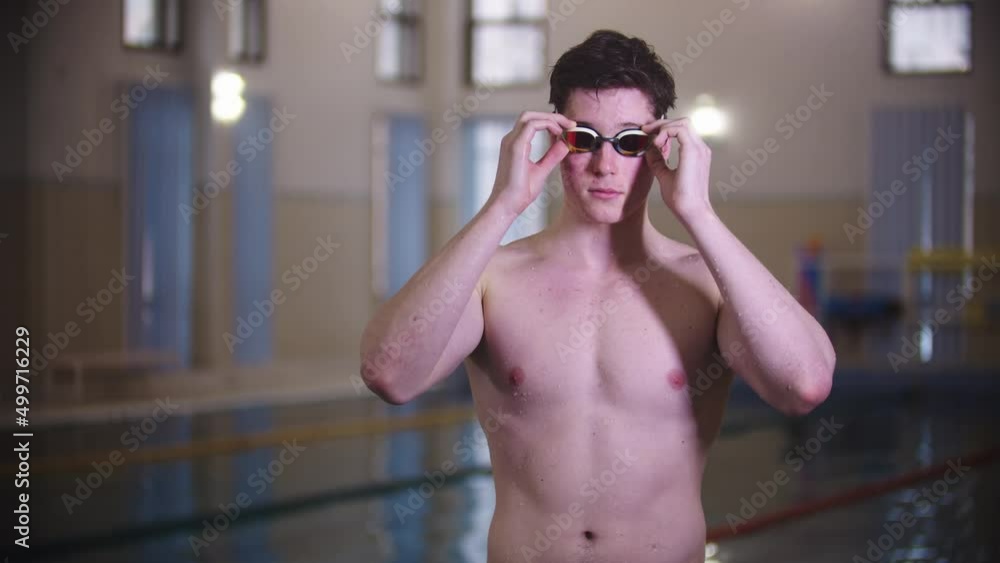A man swimmer puts on his goggles by the pool A man swimmer puts on his goggles by the pool