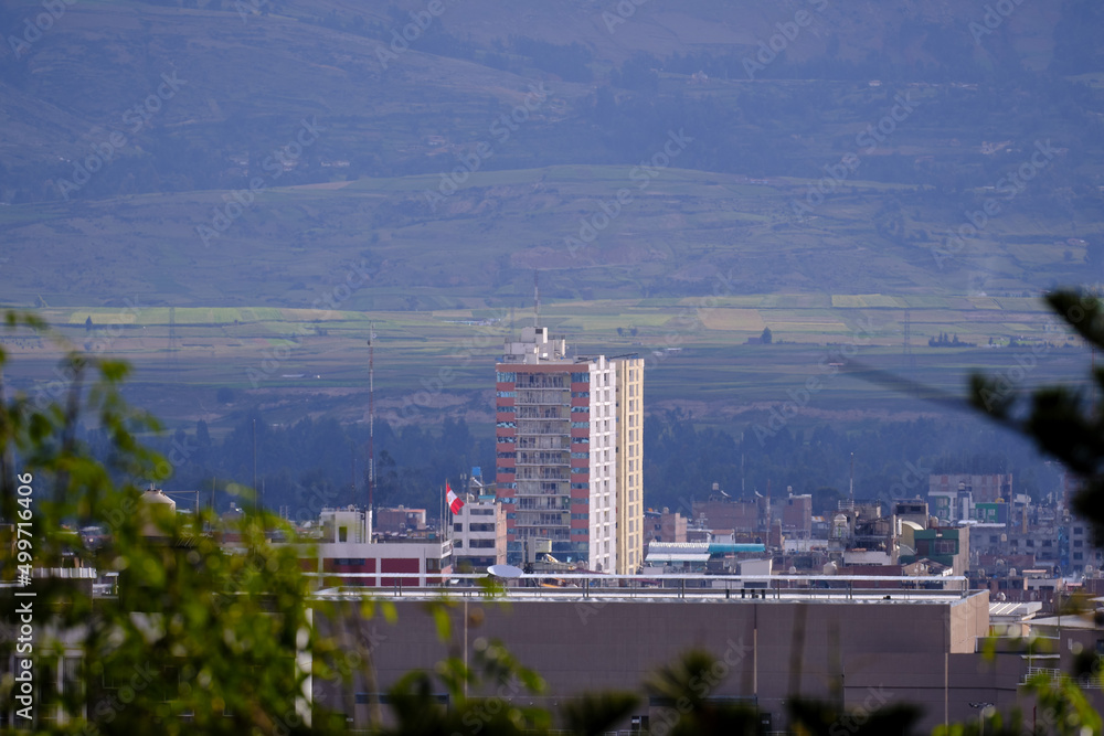 Partial view of the city of Huancayo between vegetation and the mountains in the background.
