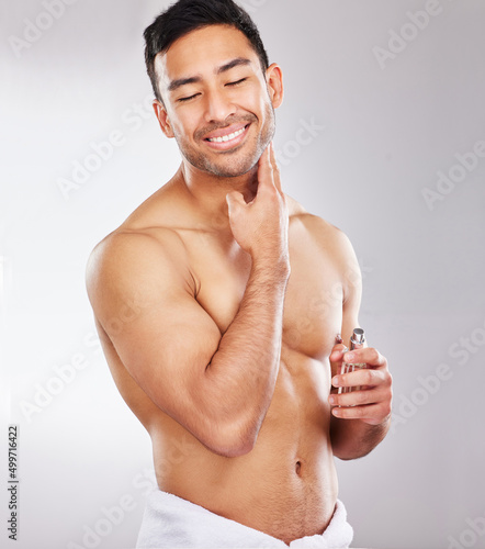 That DOES smell like rocky mountain freshness. Studio shot of a handsome young man applying aftershave.