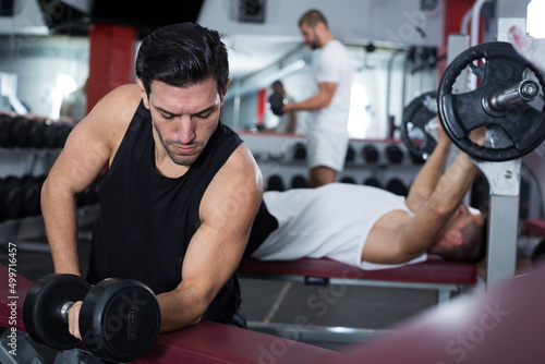 Portrait of handsome athletic man exercising with dumbbells in gym