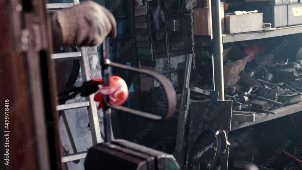 Man blacksmith puts a heated metal detail in the pressing device Man blacksmith puts a heated metal detail in the pressing device