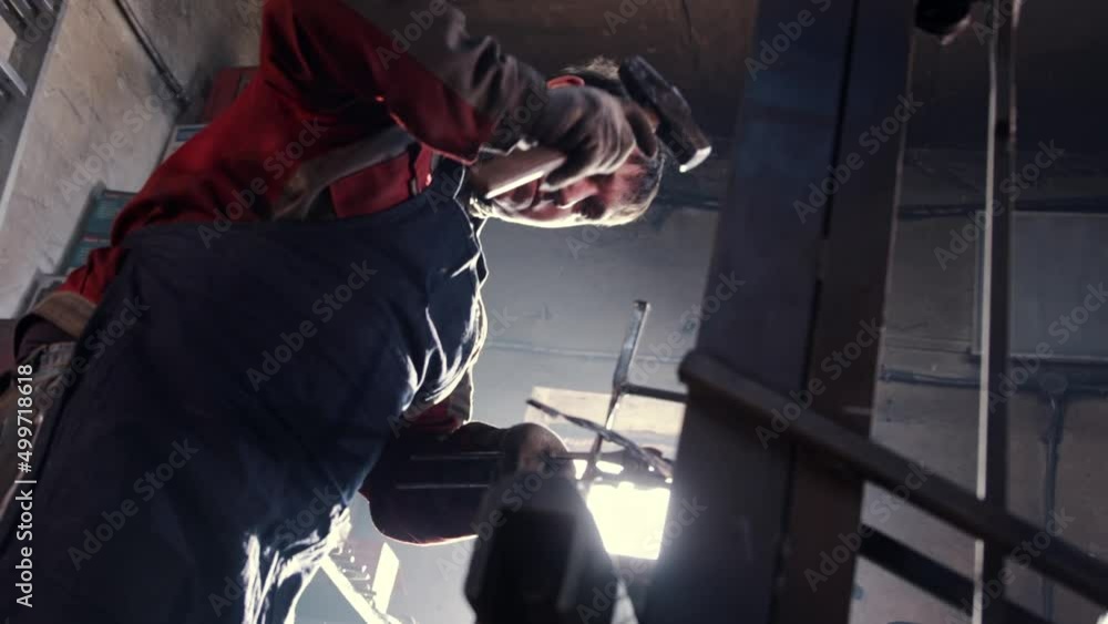 Man blacksmith hits heated detail put in sharp clips and with a hammer Man blacksmith hits heated detail put in sharp clips and with a hammer