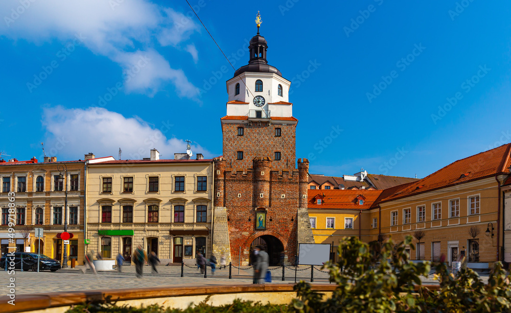 Picturesque Lublin cityscape with historic symbol of city - medieval brick gate Brama Krakowska in sunny spring day, Poland - obrazy, fototapety, plakaty 