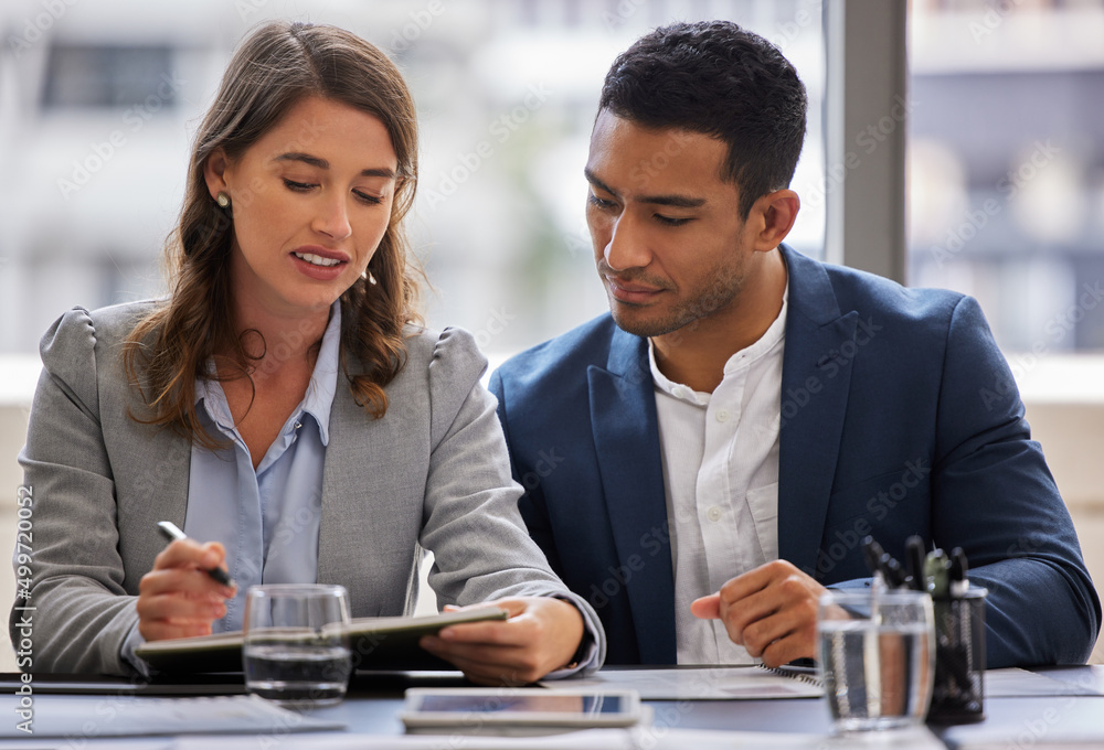 Getting a coworkers opinion. Shot of two young businesspeople sitting together in the office and having a discussion while using a digital tablet. Getting a coworkers opinion. Shot of two young businesspeople sitting together in the office and having a discussion while using a digital tablet.