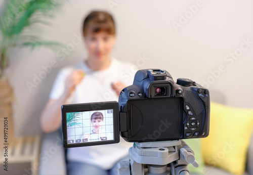 Young woman blogger recording video on camera closeup front view, selective focus.