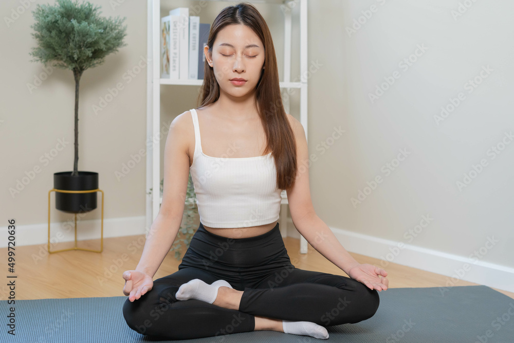 Workout, calm asian young woman, girl hand in calm pose sitting practice meditating in lotus position on mat at home, meditation, exercise for wellbeing, healthy care. Relaxation, happy leisure. Workout, calm asian young woman, girl hand in calm pose sitting practice meditating in lotus position on mat at home, meditation, exercise for wellbeing, healthy care. Relaxation, happy leisure.