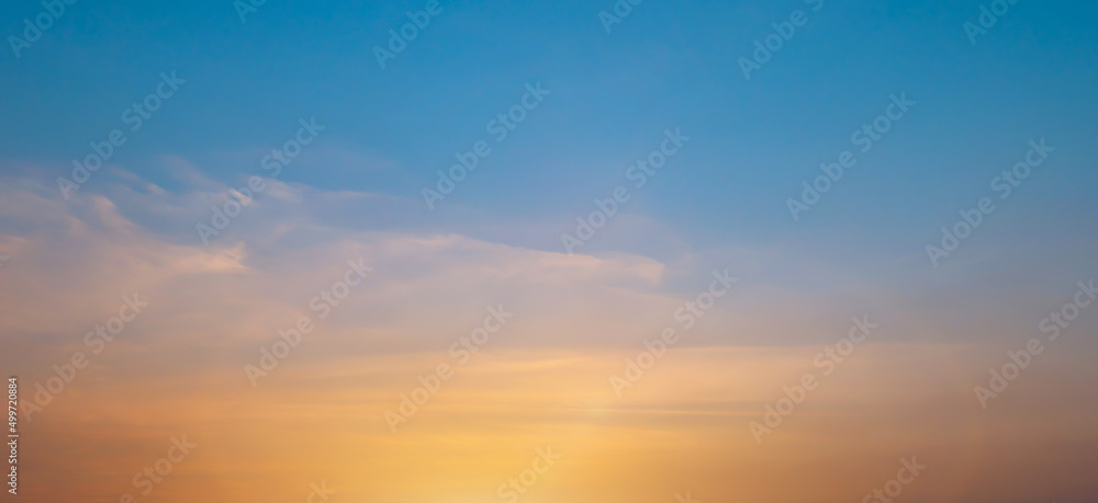 Bright orange sunset sky background with gentle colorful clouds, soft focus