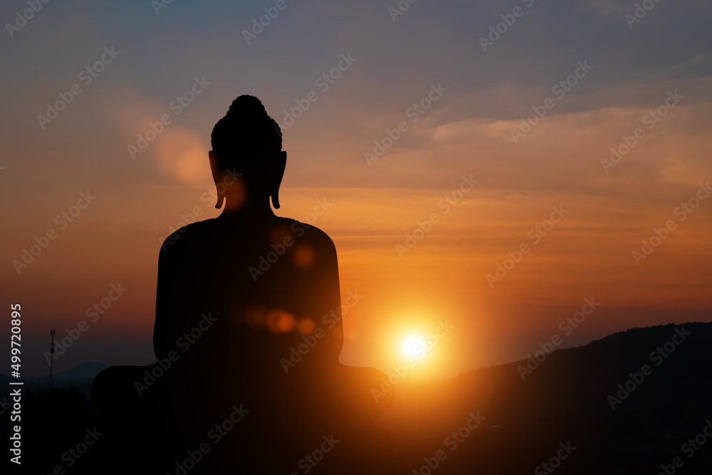 Silhouette of buddha statue at sunset sky background. Buddhist holy days concept.