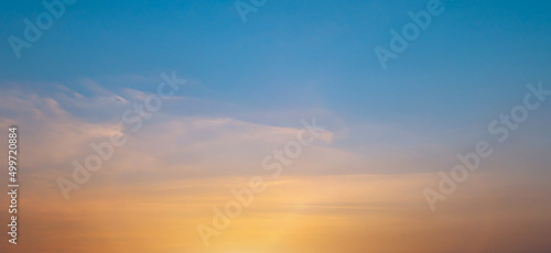 Bright orange sunset sky background with gentle colorful clouds, soft focus © banphote