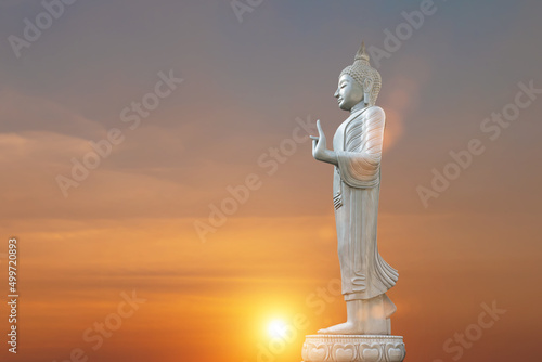 Buddha statue at sunset sky background. Buddhist holy days concept.