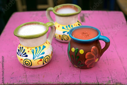traditional Mexican earthenware jars with fruit-flavored pulque, on an old Mexican pink table.
