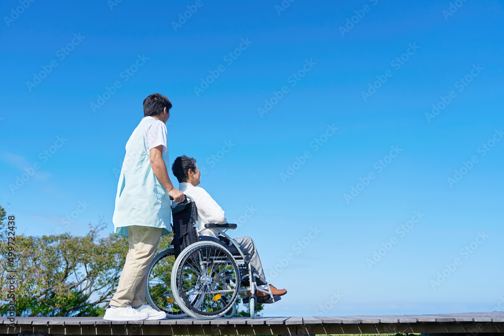 介護士と車椅子に乗った高齢者　屋外