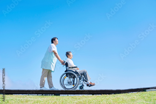 介護士と車椅子に乗った高齢者 屋外