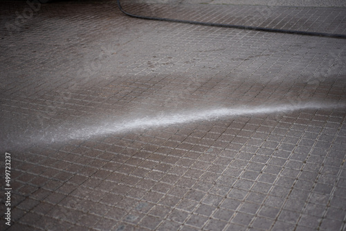 dustman cleaning street with water