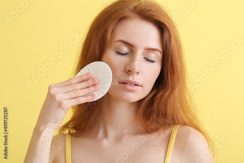 Young woman with makeup sponge on color background