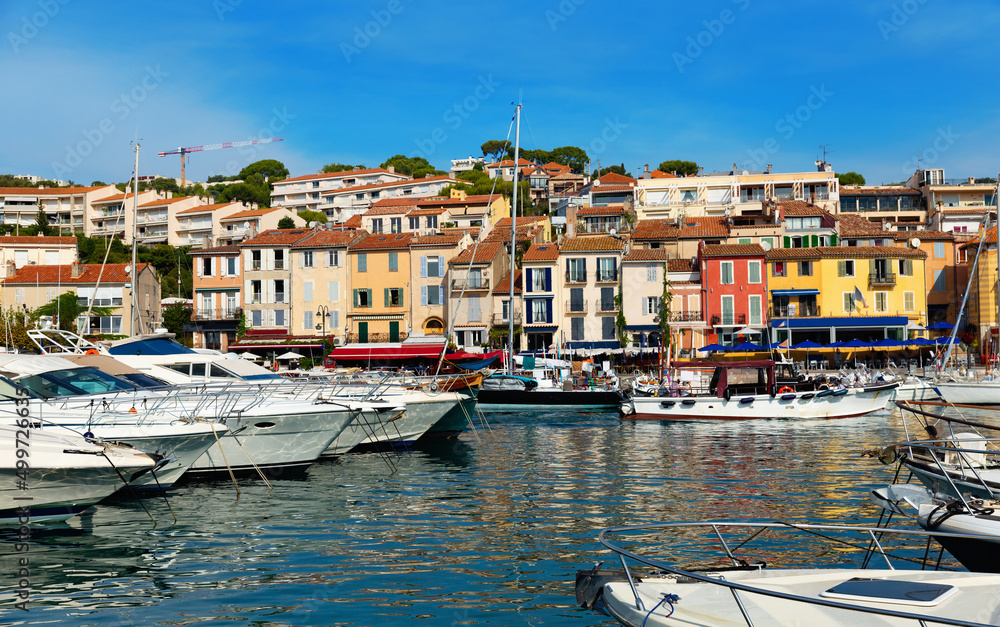 Photo of harbour in French town Cassis with view of fishing boatsand and residential buildings along shore.