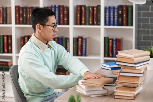 Male Asian student using la...