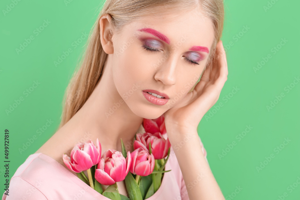 Fototapeta premium Woman with creative makeup and beautiful tulips on green background