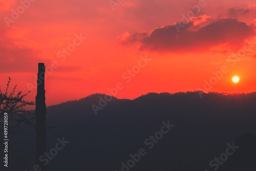 Beautiful sunset on top of mountain and round wooden stick on left © Navaashay