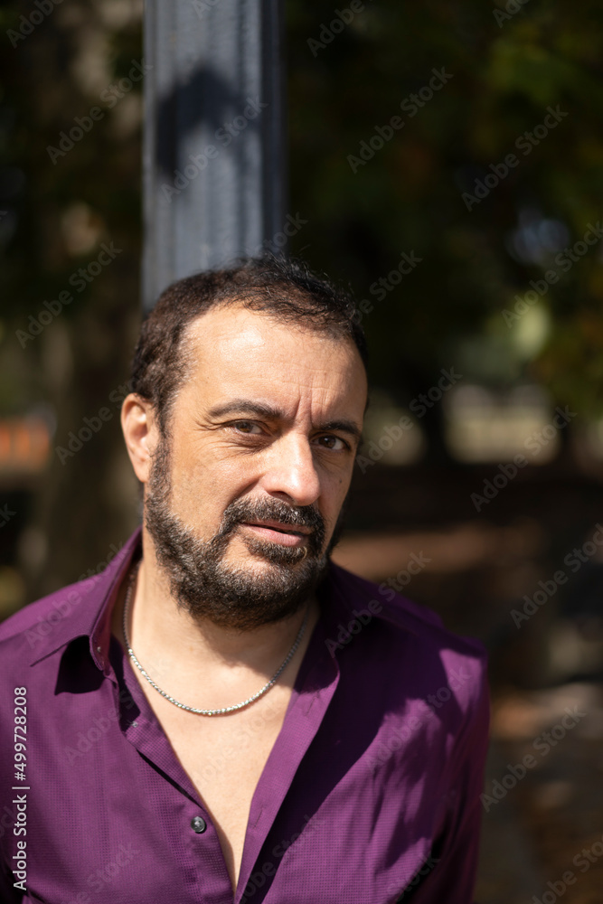 Portrait of a mature bearded man leaning on a lamp post looking at the camera Portrait of a mature bearded man leaning on a lamp post looking at the camera