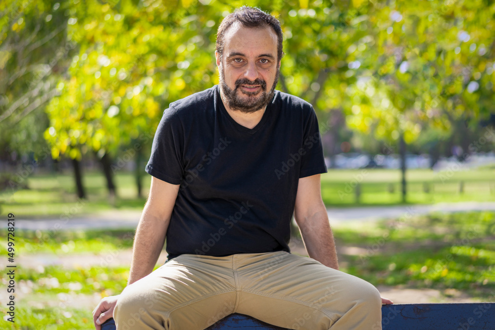 Portrait of a mature bearded man sitting in a park looking at the camera Portrait of a mature bearded man sitting in a park looking at the camera