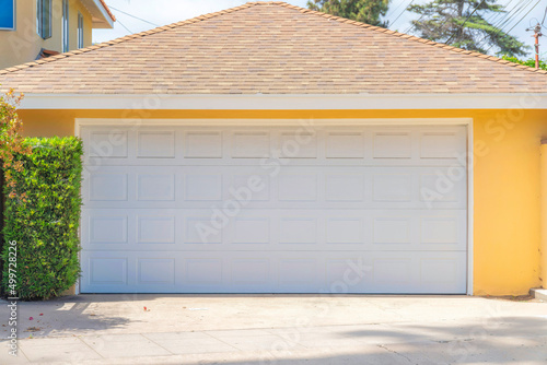 Garage exterior with yellow walls and white sectional door at La Jolla in San Diego, California