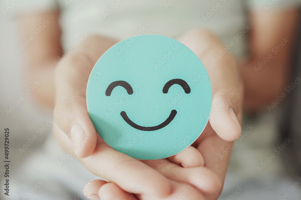 Naklejka premium Hands holding green happy smile face paper cut, good feedback rating,think positive, customer review, assessment, child wellness,world mental health day, Compliment Day