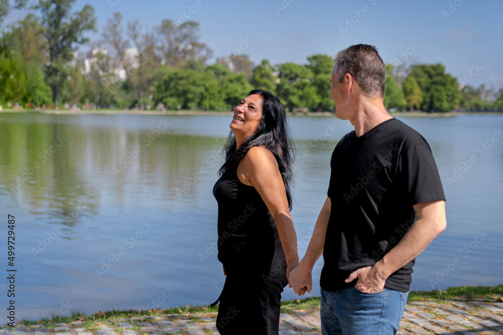 Multi-ethnic couple formed by an Andean woman and a Caucasian man walking by a lake. Happy expressions and faces of lovers Multi-ethnic couple formed by an Andean woman and a Caucasian man walking by a lake. Happy expressions and faces of lovers