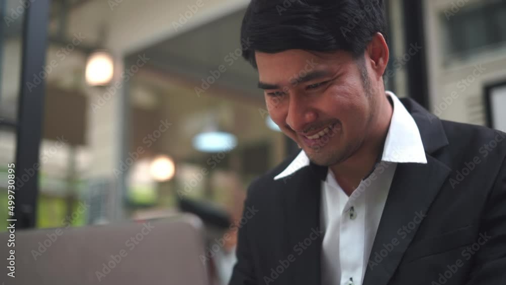 Close-up of a business man in a suit using a laptop with a smiling face Close-up of a business man in a suit using a laptop with a smiling face