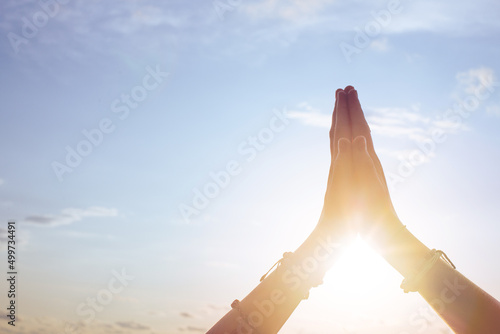 Female hands thanking the world against the sky with the sun