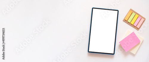 Banner with tablet with copy space, mockup on light beige background. Colorful stationery, stickers on the side. Minimalism, flat lay, top view.