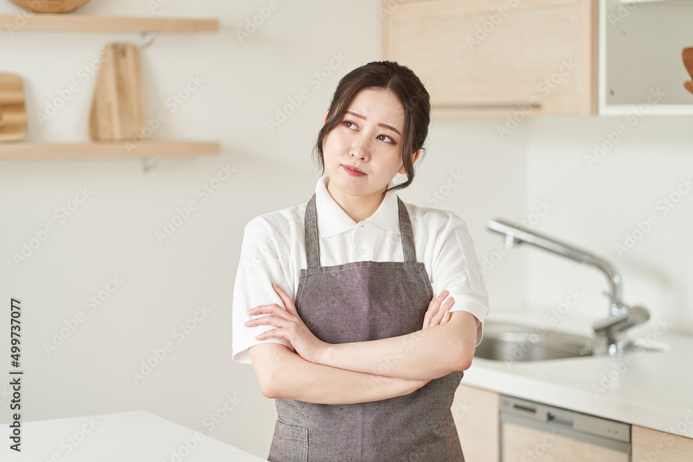 腕を組み、考え事をする家事代行業の女性 腕を組み、考え事をする家事代行業の女性